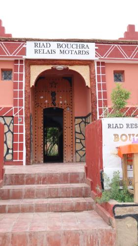 an entrance to a red brick building with a had roostricks repairs materials sign at Riad Bouchra in Tamtetoucht