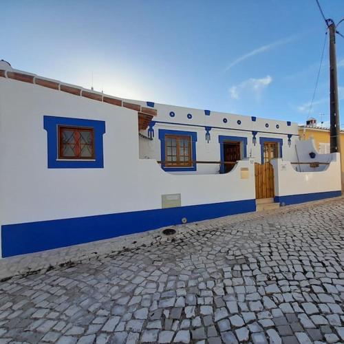 a white and blue building with a cobblestone street at Casa Martins in Barão de São João