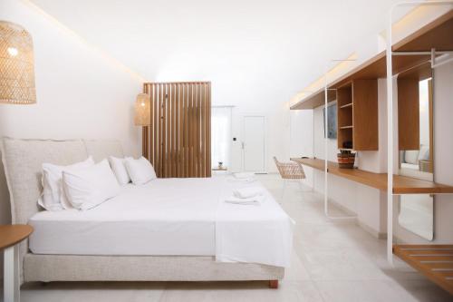 a white bedroom with a white bed and a table at Lefko Suites in Hanioti