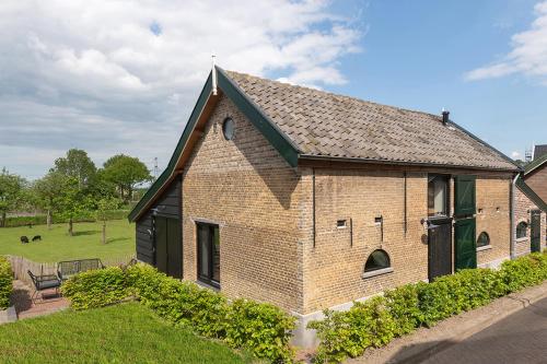a brick building with a green door in a yard at Vakantiehuisje in de polder in Oud-Alblas