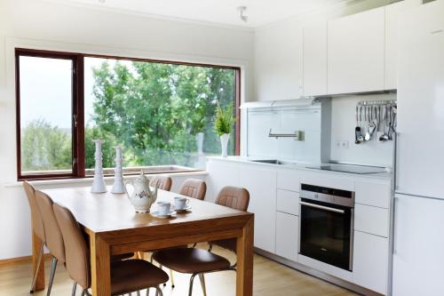 a white kitchen with a wooden table and chairs at Fagrahlíd Guesthouse in Hvolsvöllur