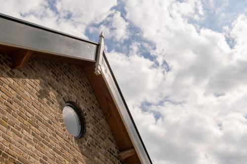 a brick building with a circular window on a cloudy sky at Vakantiehuisje in de polder in Oud-Alblas