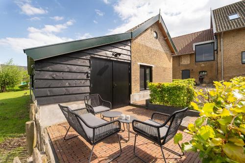 a patio with chairs and a table and a building at Vakantiehuisje in de polder in Oud-Alblas
