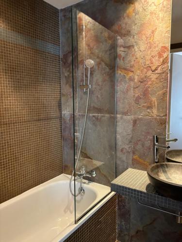 uma casa de banho com um chuveiro, uma banheira e um lavatório. em Hotel Moulin Plaza em Paris