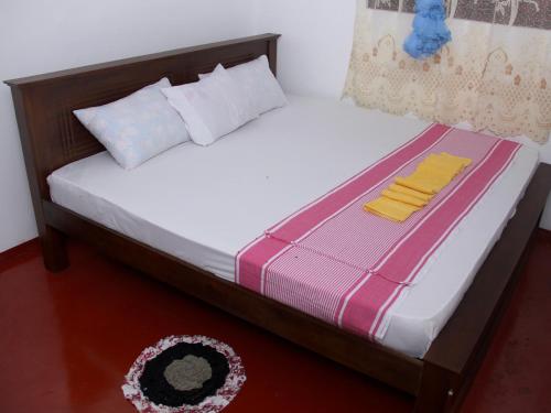 a bedroom with a bed with white sheets and a rug at Dilan Guest in Mirissa