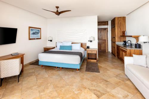 een slaapkamer met een bed en een bank bij Cabo Surf Hotel in San José del Cabo