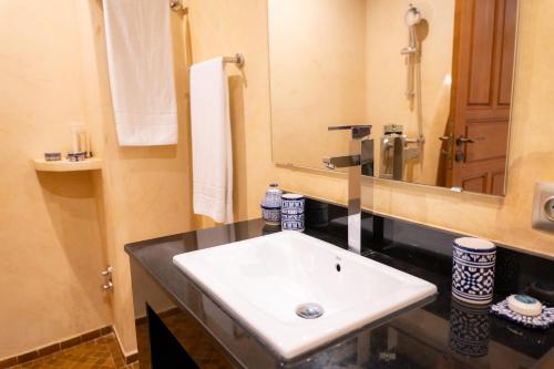 a bathroom with a white sink and a mirror at Riad Al Ansari in Fès