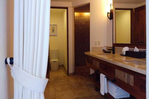 a bathroom with a sink and a large mirror at Cabo Surf Hotel in San José del Cabo