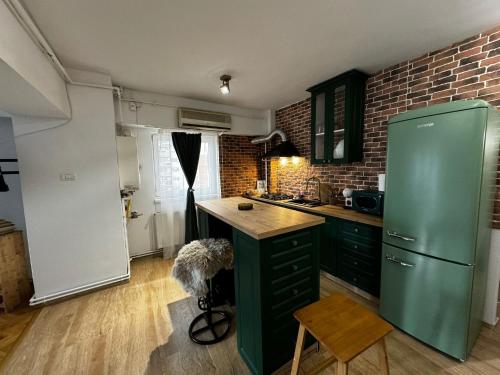 a kitchen with a green refrigerator and a brick wall at Rosa Apartment in Drobeta-Turnu Severin