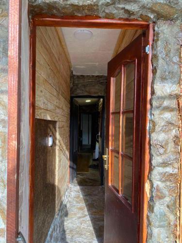 an open door into a hallway with a stone wall at Smeštaj Popović in Perućac