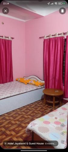 two beds in a room with pink curtains and a table at Jayalaxmi guest House in Birātnagar