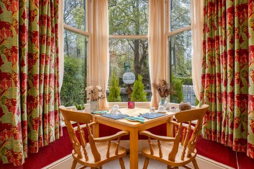 ein Esszimmer mit einem Tisch, Stühlen und einem Fenster in der Unterkunft Burnside B&B in Keswick