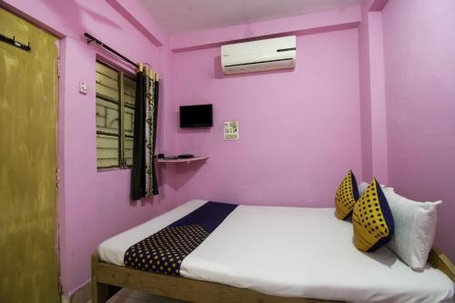 a bedroom with pink walls and a bed with pillows at OYO Hotel Suvidha in Jamshedpur