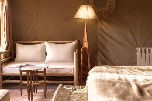 Habitación con sofá, mesa y lámpara. en Caravanserai Luxury Desert Camp, en Merzouga