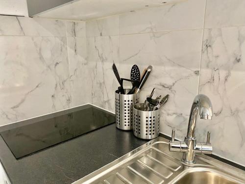 eine Küchentheke mit einer Spüle und Küchenutensilien in der Unterkunft Remarkable Apartment in London in London
