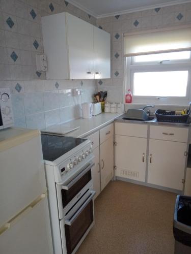 a kitchen with white cabinets and a stove top oven at Chalet at California Sands in Scratby