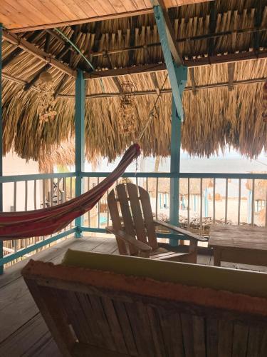 a hammock and a chair in a straw hut at Palenque Beach House in San Onofre