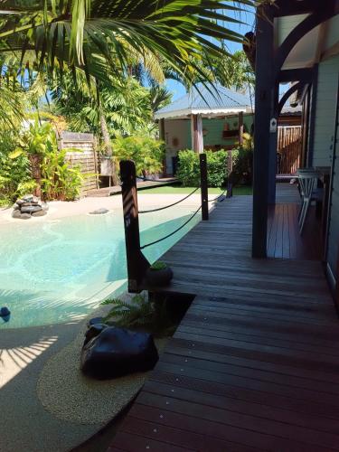 a wooden walkway next to a swimming pool at TIKI PARADISE LODGE FWI in Sainte-Anne