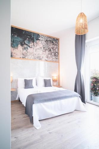 a white bedroom with two beds and a painting on the wall at New Elegance Suites Guesthouse in Oristano