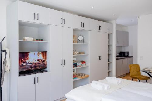 a white bedroom with a bed and a tv on a wall at Lumen Homes - Altstadt-Studio direkt im Zentrum, Küche, öffentlicher Parkplatz ums Eck in Ingolstadt