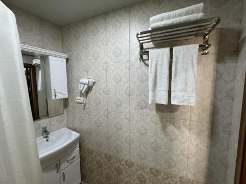 a bathroom with a sink and a toilet and towels at Al-Khabib in Bukhara