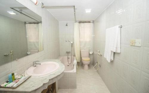 a white bathroom with a sink and a toilet at Hotel Suite Palace Baridhara in Dhaka