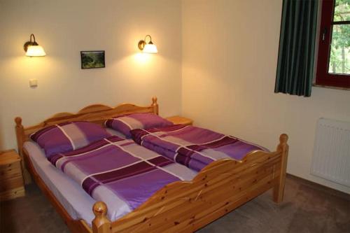 a bedroom with a wooden bed with purple sheets at Ferienwohnungen auf dem Landgut Elshof 