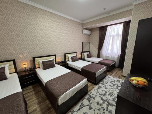 a hotel room with three beds and a table at Al-Khabib in Bukhara