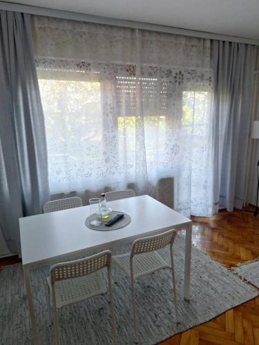 biały stół i krzesła przed oknem w obiekcie Apartment Ljiljan 2 Niš w Niszu