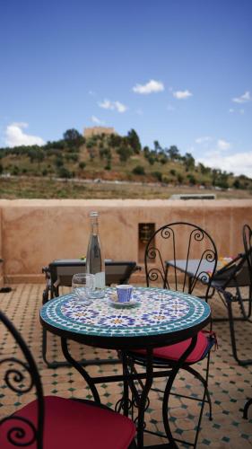 a table with a glass bottle and chairs on a patio at Riad Jamal in Fès