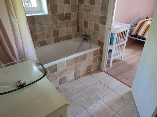 une salle de bain avec baignoire et sol carrelé dans l'établissement Charmante Villa avec piscine proche de St-Emilion, à Pellegrue