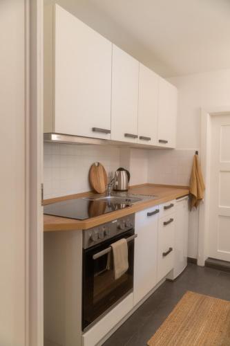 a kitchen with white cabinets and a stove top oven at Modernes Altstadt Apartment in Bad Belzig
