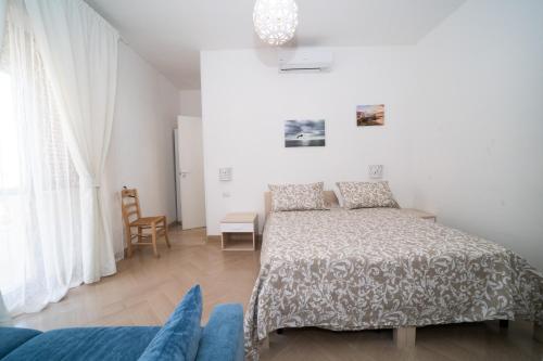 biała sypialnia z łóżkiem i krzesłem w obiekcie Villa Cristina B&b Alezio w mieście Alezio