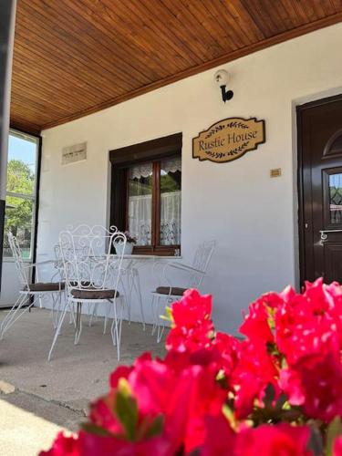 a patio with white chairs and tables and pink flowers at Rustic House in Miléa