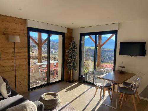 un salon avec une table, des chaises et une télévision dans l'établissement Les vignes du château 2, à Chorges