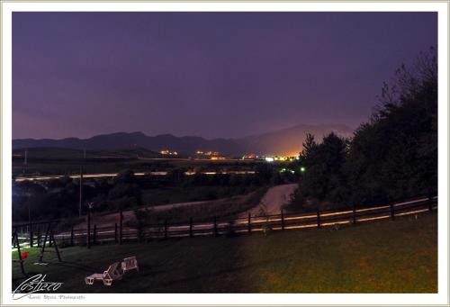 um campo com uma cerca e uma estrada de terra à noite em Dumbrava Ursului em Zarnesti