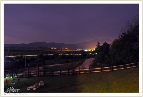 a field with a fence and a dirt road at night at Dumbrava Ursului in Zărneşti