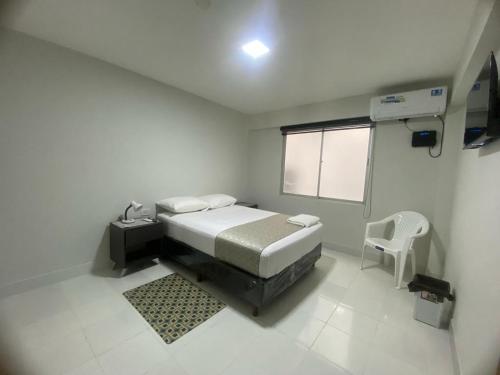 Kleines weißes Zimmer mit einem Bett und einem Stuhl in der Unterkunft Hostal Independencia in Santa Cruz de la Sierra