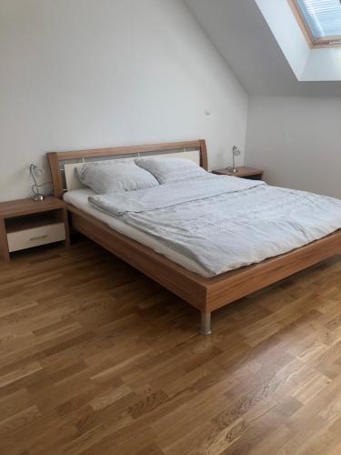 a bed in a white room with wooden floors at Wypoczynek nad Dunajcem 