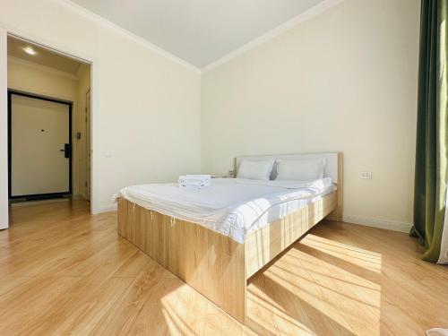 ein großes Bett in einem Zimmer mit Holzboden in der Unterkunft Grand Turan Comfort Two-Room Apartments in Astana