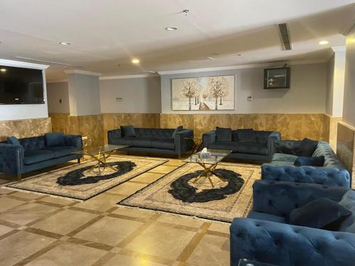 a living room with blue couches and a tv at فندق مساكن اللؤلؤة in Al Masfalah