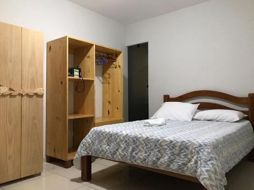 1 dormitorio con 1 cama y armario de madera en Taocas Flats Maragogi, en Maragogi