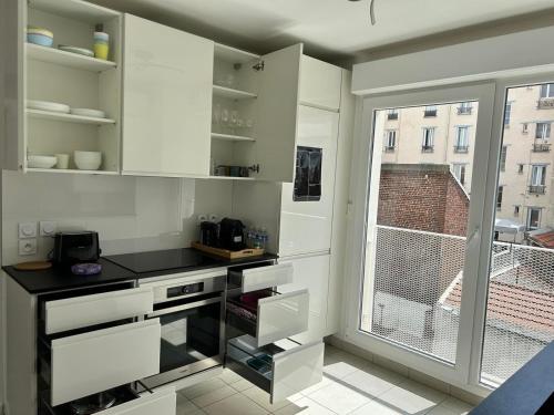 uma cozinha com armários brancos e uma janela em Le 147 Parc Entre Paris et Disney em Champigny-sur-Marne