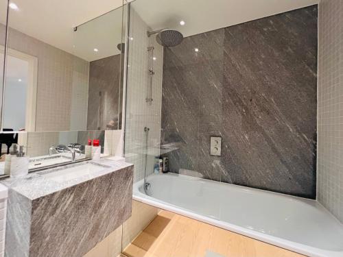 La salle de bains est pourvue d'une baignoire, d'un lavabo et d'une douche. dans l'établissement Lovely 2Bedroom Apartment at O2 London 01, à Londres