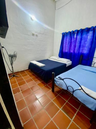 a room with two beds and a blue curtain at El Palmar in Guaduas