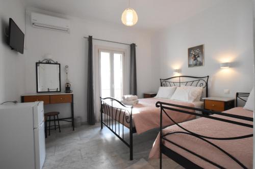 1 dormitorio con 2 camas, escritorio y espejo en Asteri Hotel en Ornos