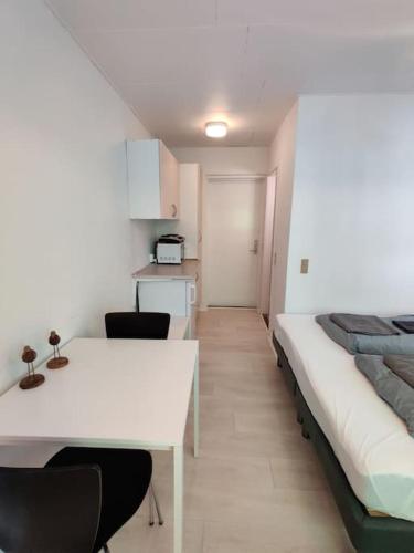 Habitación con cama, mesa blanca y sillas. en Lille hyggelig centrum lejlighed! No17, en Billund