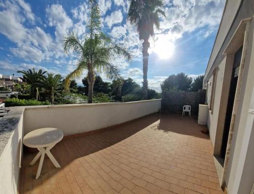 a patio with a table and a chair and palm trees at LaCasAMare in Molfetta
