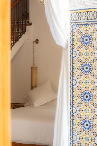 a bedroom with a bed and a white curtain at Riad Al Ansari in Fès