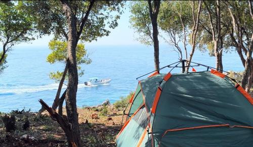 a tent with a boat in the water at Camping Aquarium in Himare
